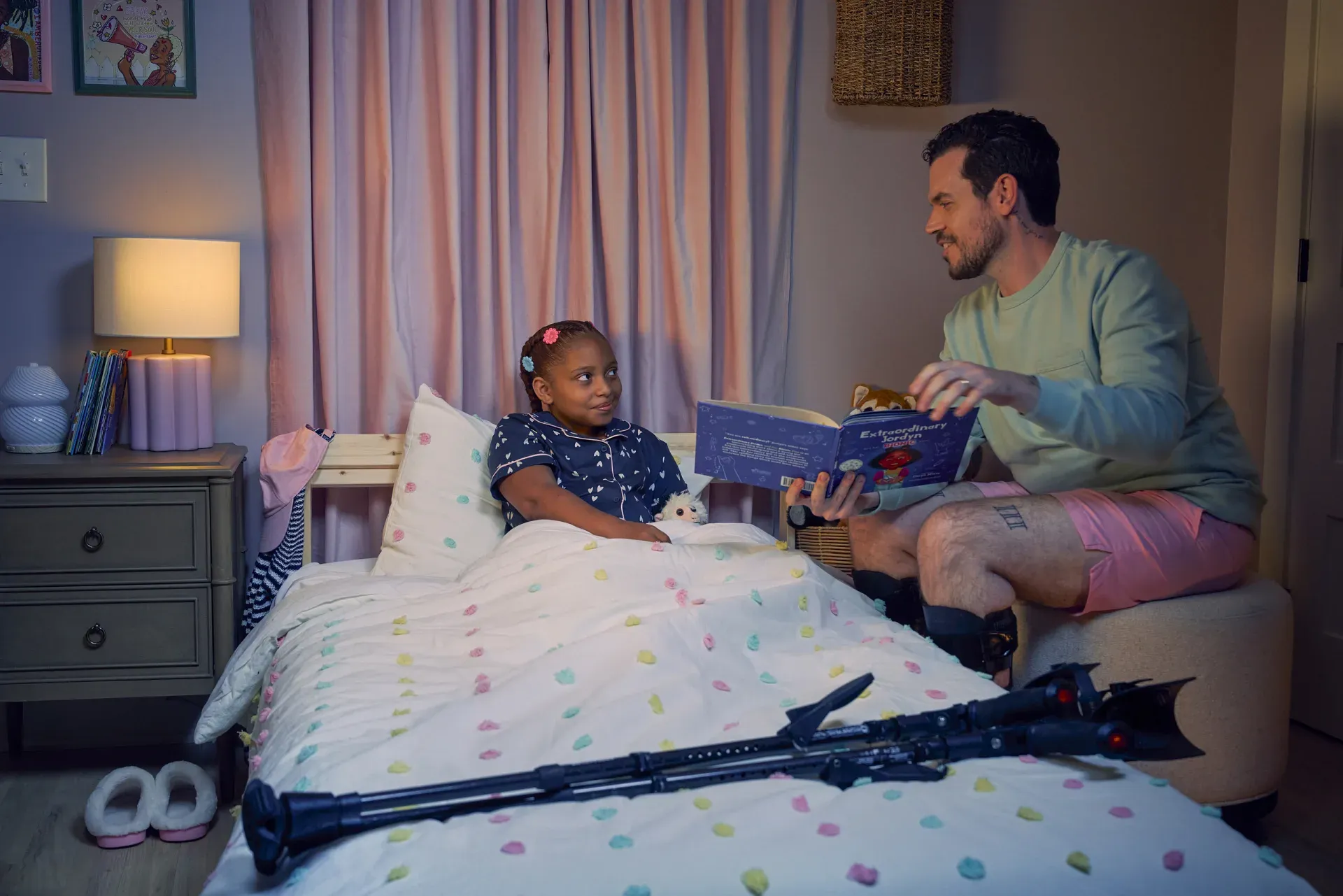 A parent reading a bedtime story to a child beside her mobility equipment.