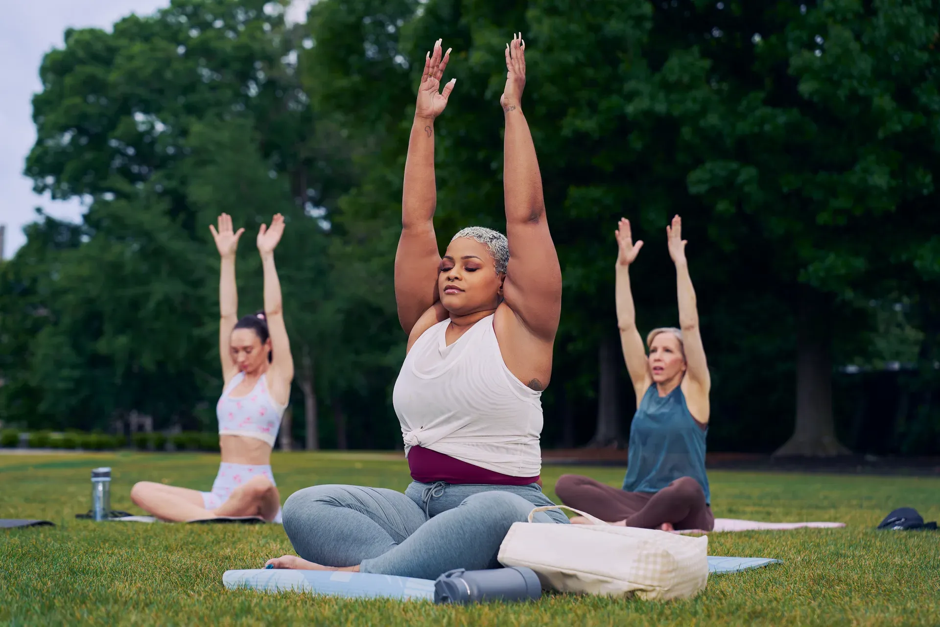 Three people practicing yoga together outdoors.