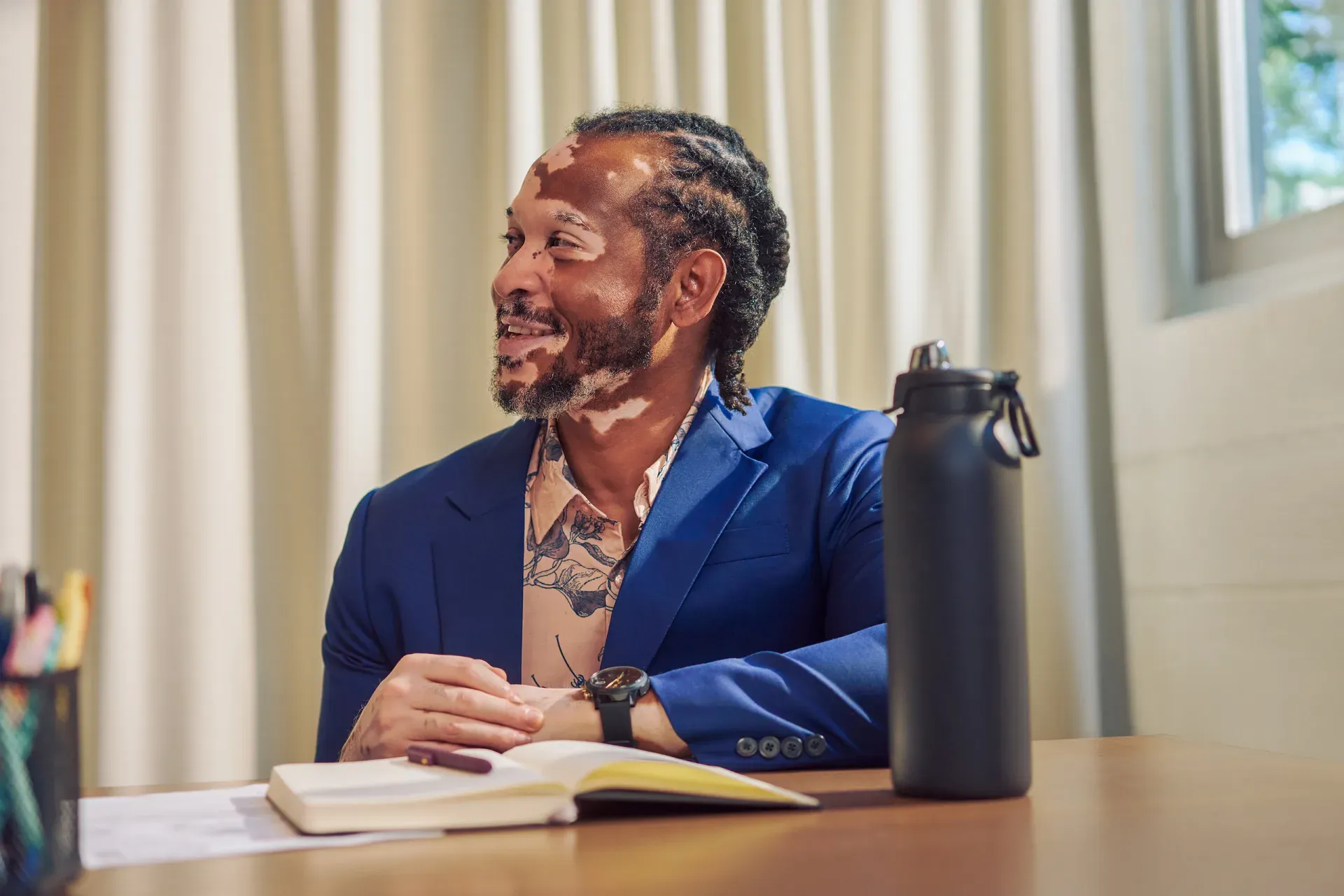 A professional in a blue suit participating in a meeting at a table.